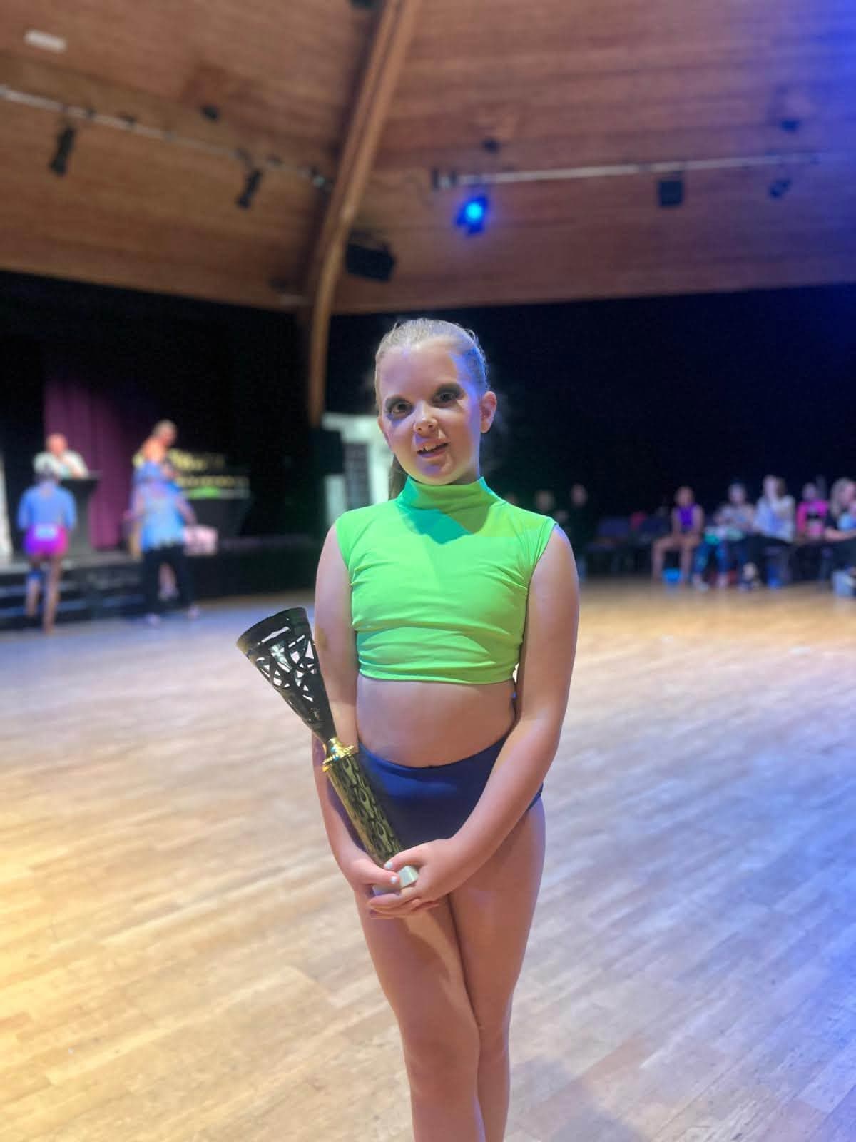 Solo dancer with trophy in lime and navy costume